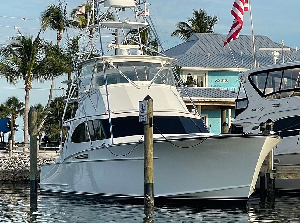 A newly repowered 54-foot Rybovich sportfishing yacht docked at shore with palm trees and a building in the background