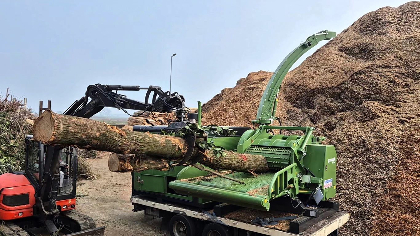 Pezzalato’s PTH 1200 industrial wood chipper powered by a JD14 engine chipping a log into a large pile of wood chips