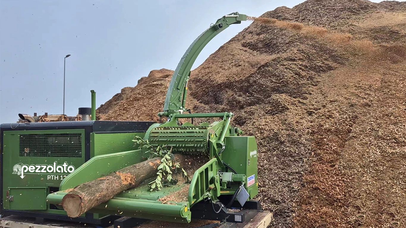 Pezzalato’s PTH 1200 drum wood chipper powered by a JD14 industrial engine chipping a small log into a large pile of wood chips