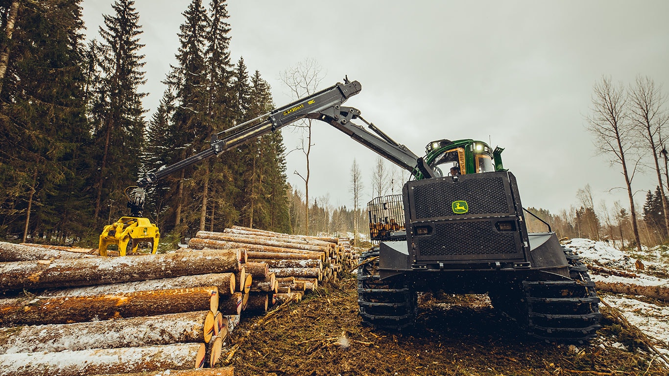 2510H forwarder with extended boom in a forested logging area.