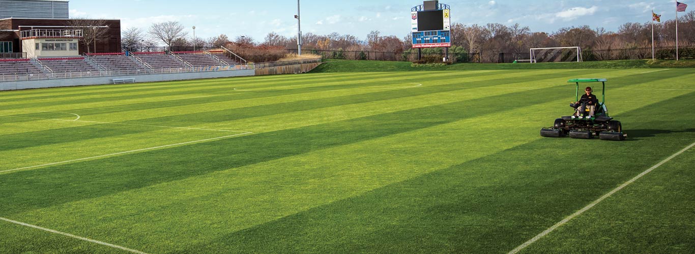 person on a mower in a stadium field