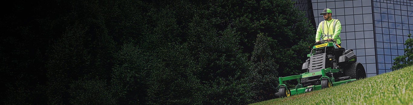 A landscaping operator mowing corporate grounds on a John Deere Q850R QuikTrak™ Stand-On mower.