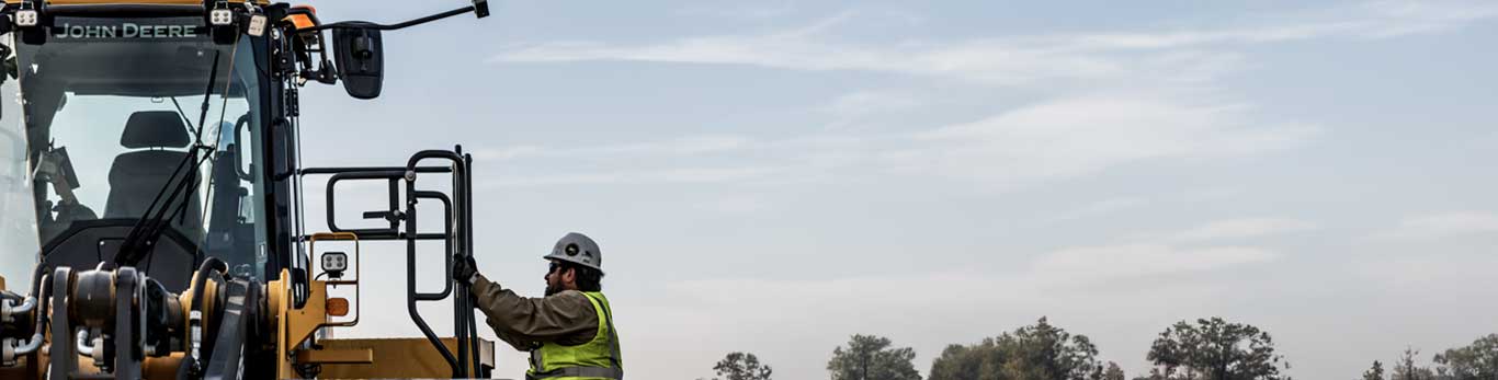 Trainee climbing on the John Deere construction equipment