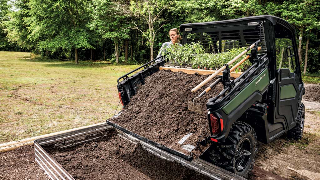Person dumping dirt from the cargo box of a XUV 845M Person dumping dirt from the cargo box of a XUV 845M