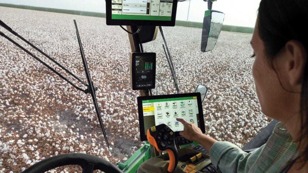 an in-Cab shot showing an operator interacting with a G5Plus CommandCenter&trade; Display in a John Deere cotton harvester