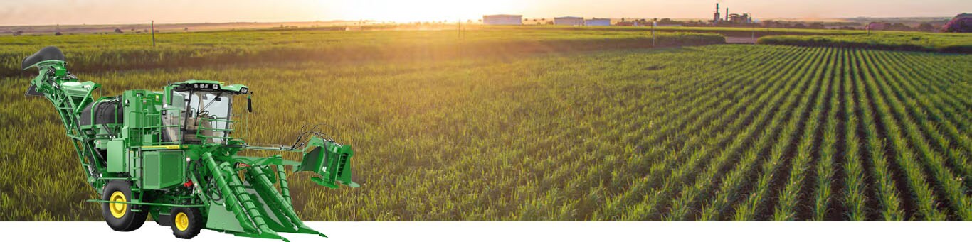 A photo of a partially-harvested sugar cane field with the sun rising on the horizon. A John Deere CH Series Sugar Harvester is inset into the lower left hand corner of the image.