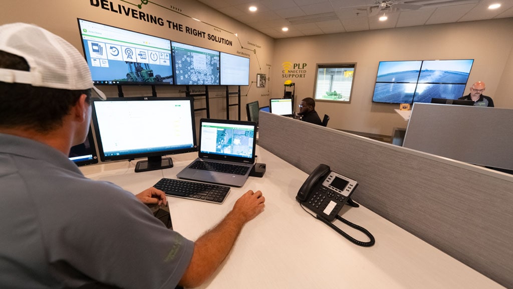 Photo of a John Deere technician, in a customer support center, providing online support to a customer
