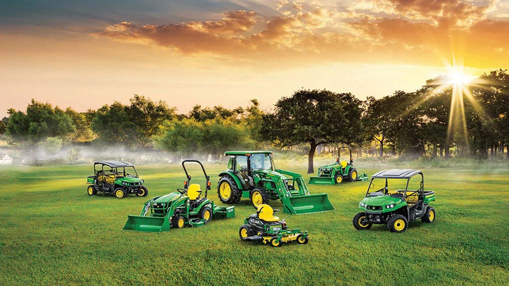 Gators, mowers, tractors in a field during sunrise.