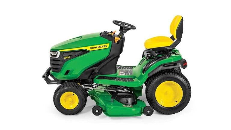 A left-facing green riding mower with a yellow seat and green mowing deck on a white background. (4th thumbnail)