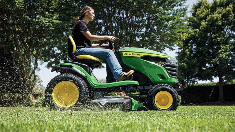 Close-up of grass being blown out the side of a green deck attached to a green riding mower. (10th thumbnail)