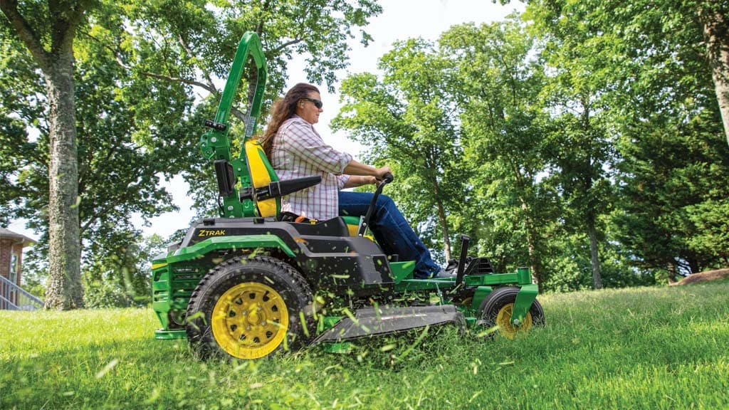 Person riding a ztrak mower cutting grass in a sunny park