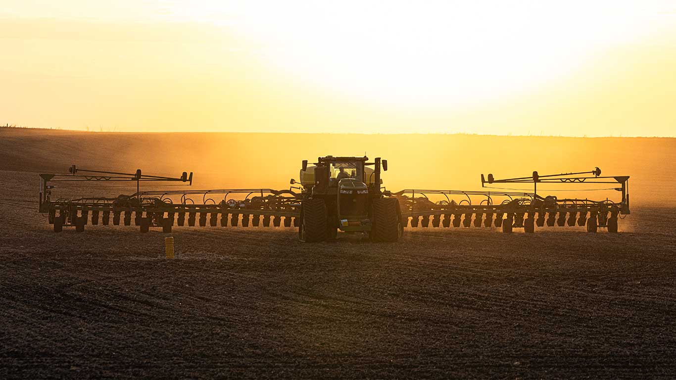 9 Series Tractor with drawn planter in field at sunset