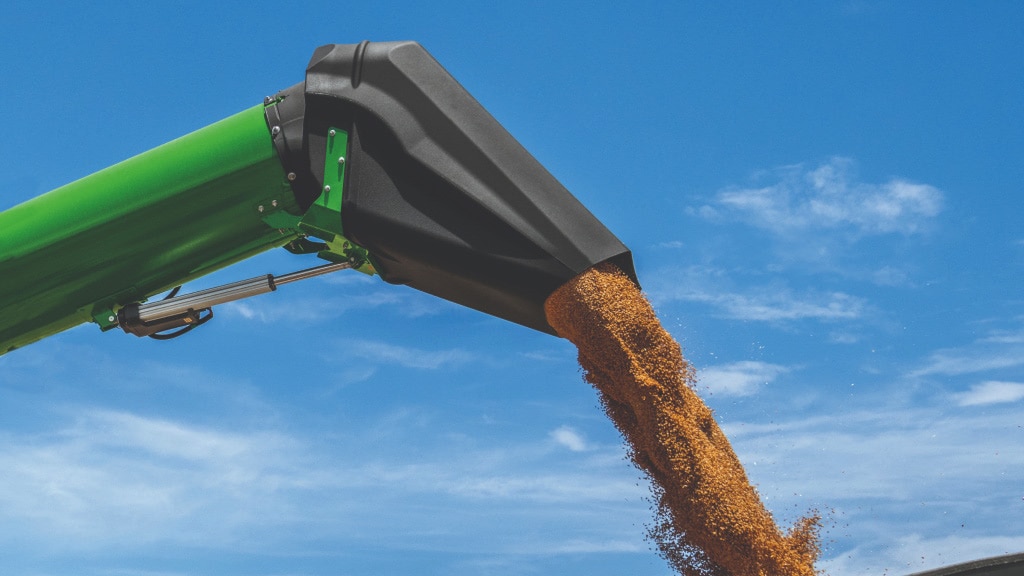 Close-up photograph of the Adjustable Auger Spout unloading grain into a grain cart.