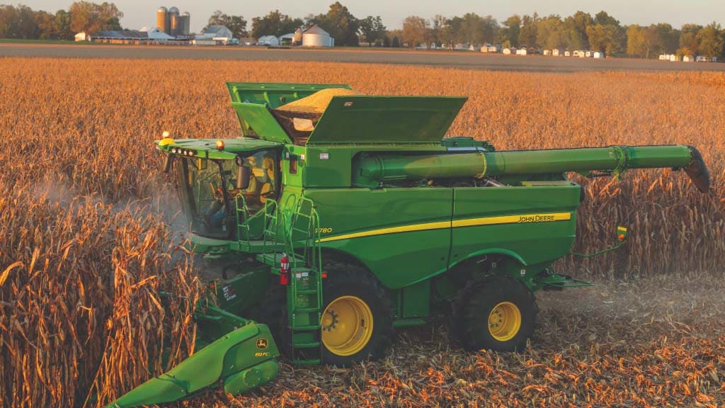 Photograph of a S780 combine harvesting corn with a corn head.