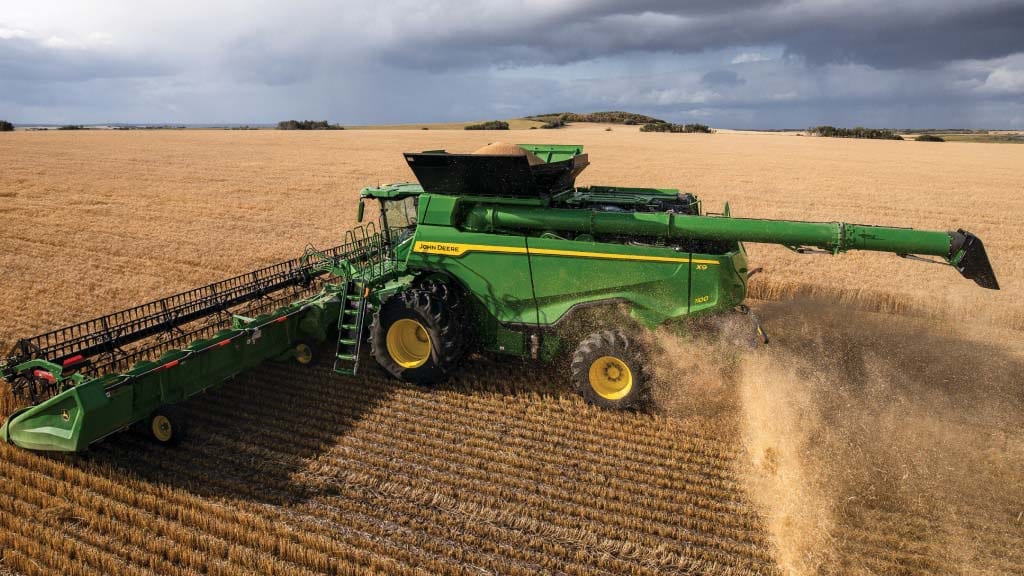 Photograph of an X9 1100 Combine harvesting small grains, spreading residual from the improved residue management system.