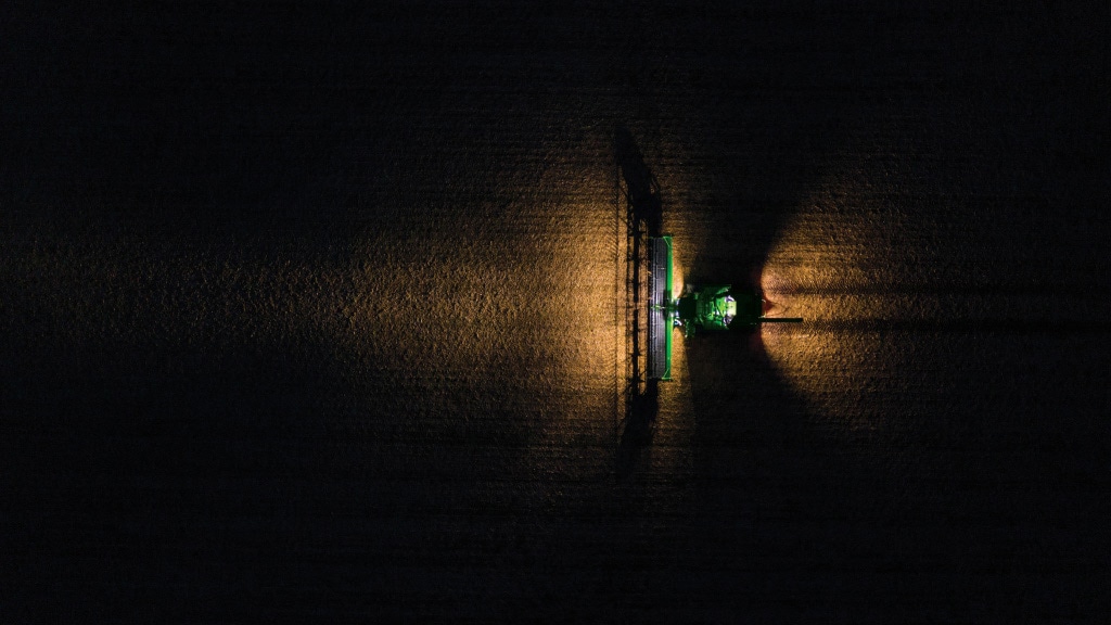 Overhead photograph of a combine harvesting at night, with the darkness illuminated by LED Lights.