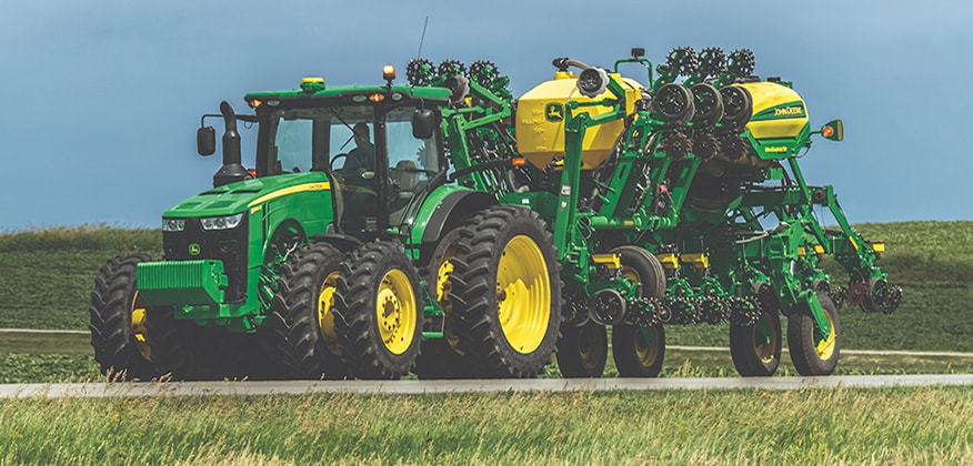 8R tractor with planter on the road.