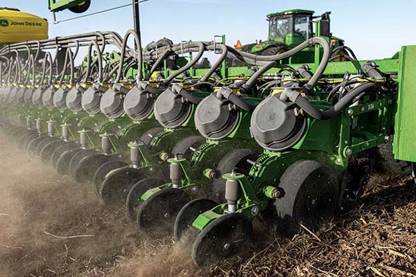Close-up photograph of the row units on a John Deere planter in action.