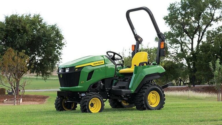 A flat open field has a green compact tractor with a yellow seat resting on it. (5th thumbnail)