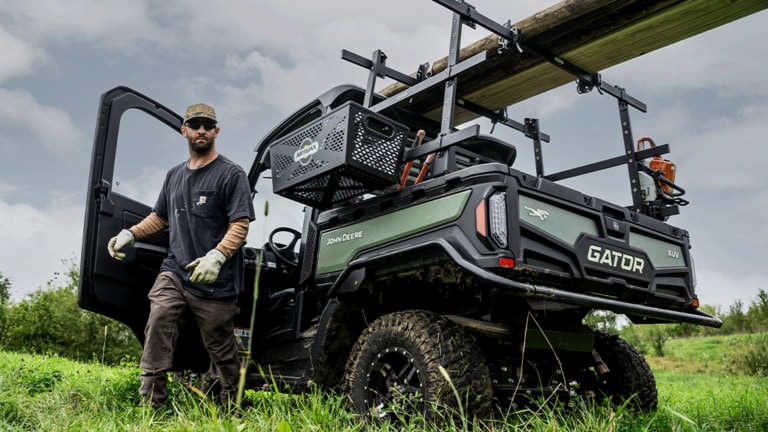 A HVAC cabbed olive-green Gator carrying timber and tools on the racks over its cargo box. (14th thumbnail)