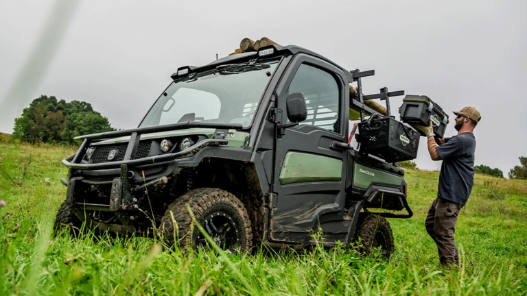 A toolbox is loaded onto the side rack of an olive-green Gator. (15th thumbnail)