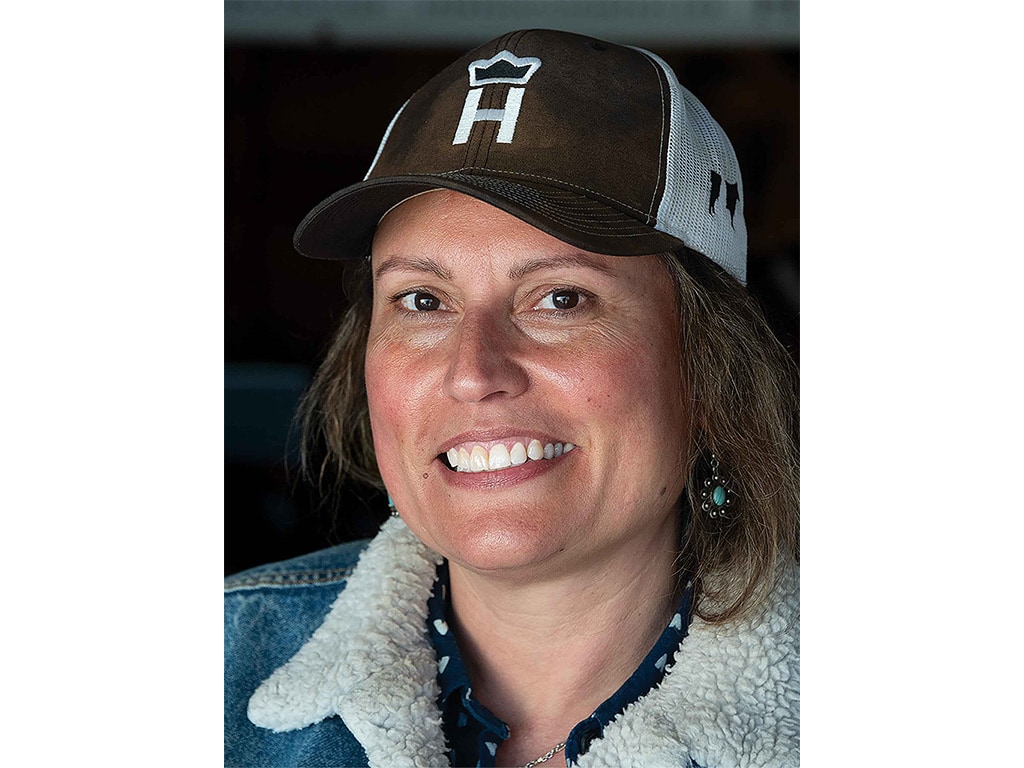 Smiling cattle farmer with black and white baseball cap and shearling-lined denim jacket