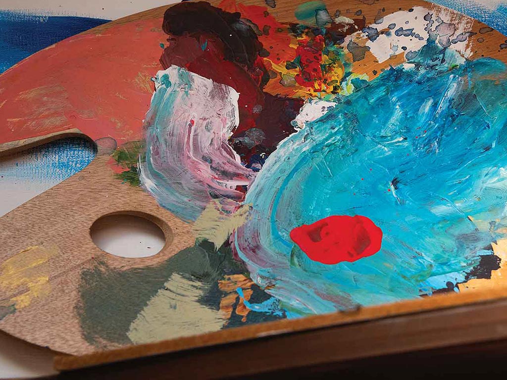 An artist's paint palette smeared with various colored paint