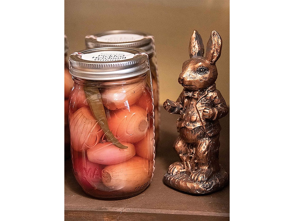 two jars of pickled vegetables with a bronze rabbit statue beside