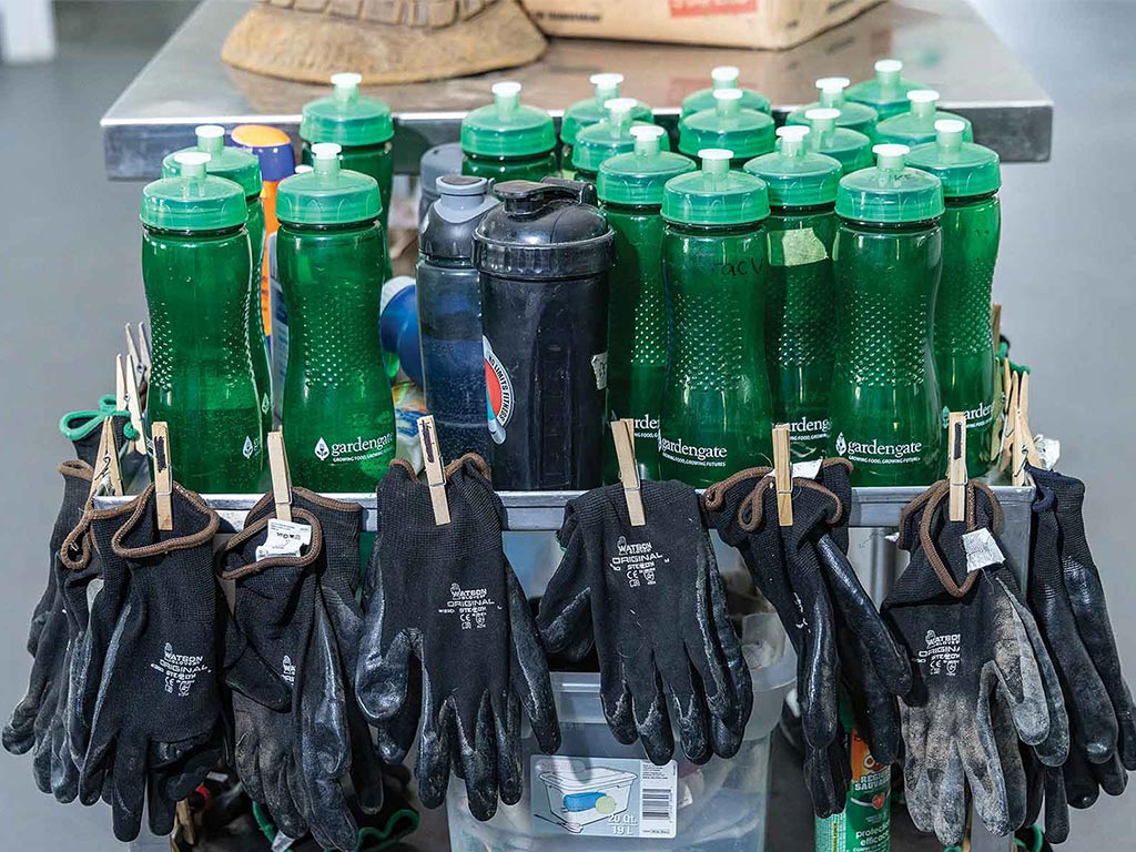 green plastic water bottles with pairs of black work gloves clothespinned to the edge of a cart