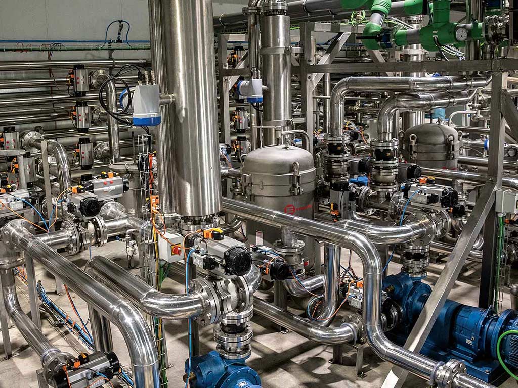 the shiny stainless steel maze of pipes and kettles of the olive oil processing facility