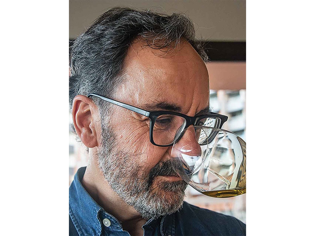 closeup of a person smelling olive oil in a small glass