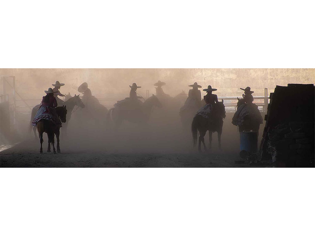 a dusty silhouetted panorama of the riders assembling in a covered area on horseback