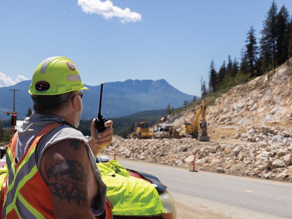 construction worker with a hand radio looking at a construction site 