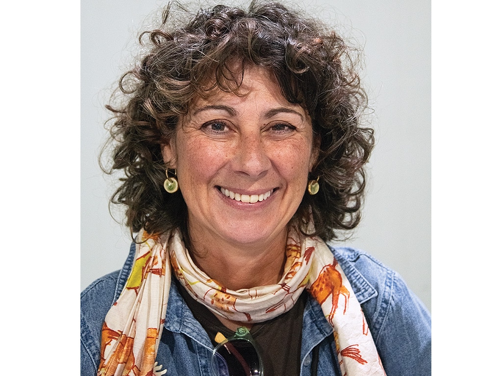 smiling person with orange and white scarf and blue denim shirt