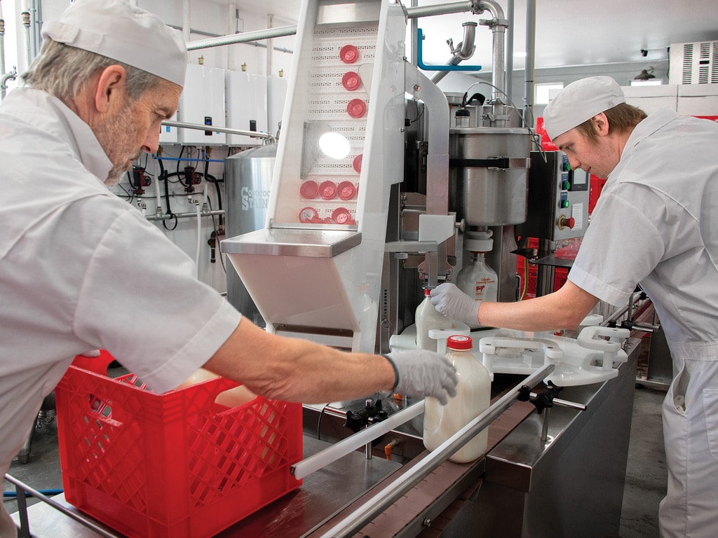 two people bottling milk in a factory