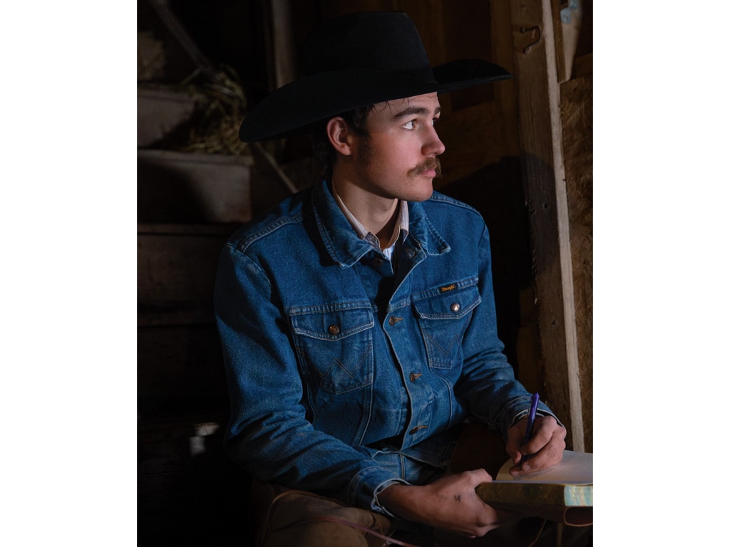 person in a cowboy hat writing in a book