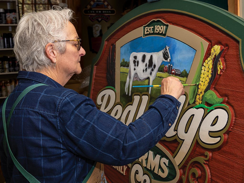 Noella Cotnam painting corn on a farm sign