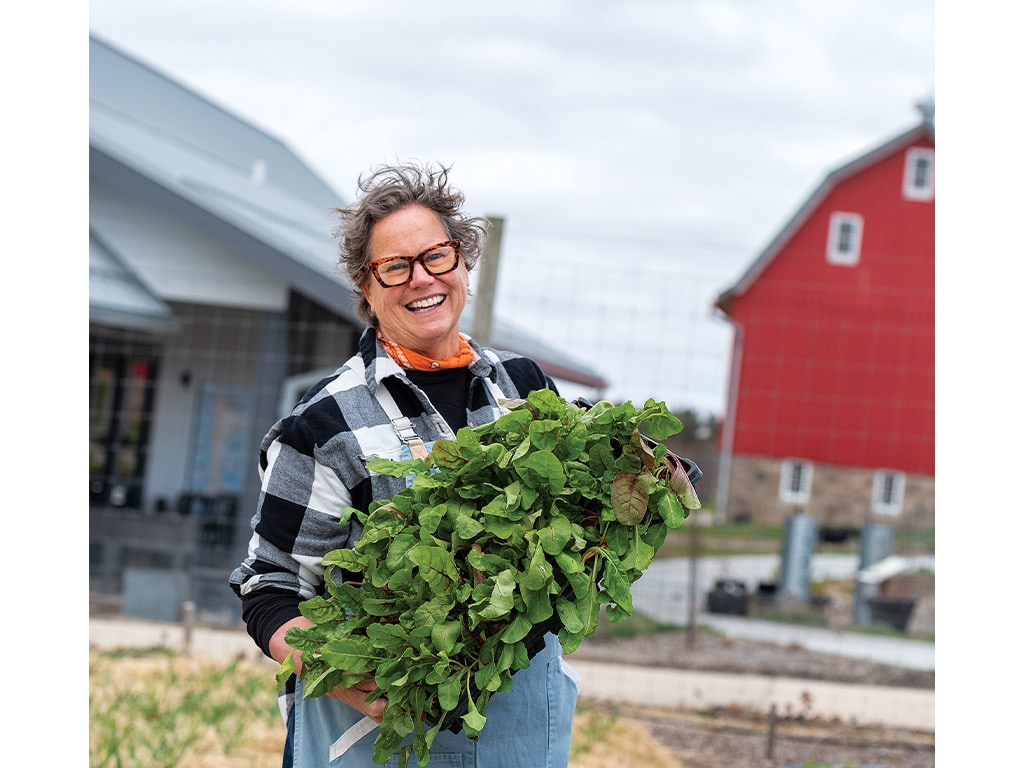 Beth Fisher with a tray full of herbs smiling