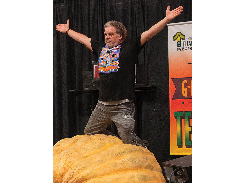 Ron Barker kneeling on his pumpkin with arms raised