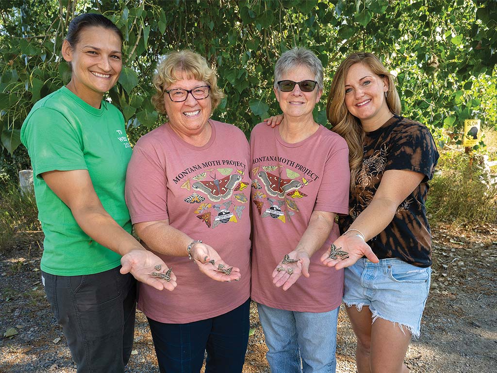 citizen scientists Rebecca Mathias, Claudia Fife, and Mary Mullen and Kirst smiling while holding moths