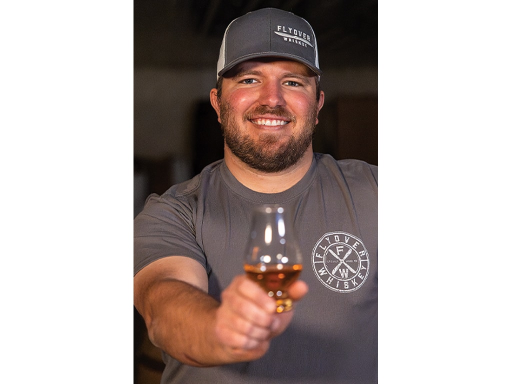 Joe Knobbe smiling holding a glass of whiskey