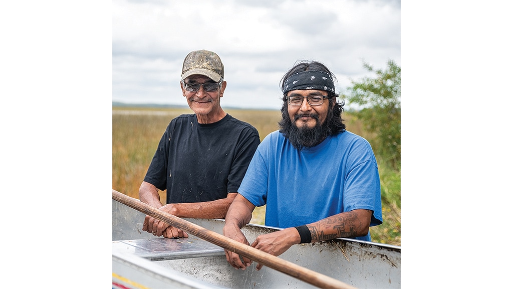 two men smiling for a pose placing their hands on boat