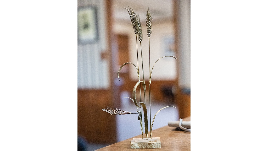 a figure of 3 stalks of wheat on a flat rock base on a table