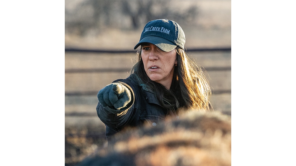 woman wearing black cap showing her finger at cows herd