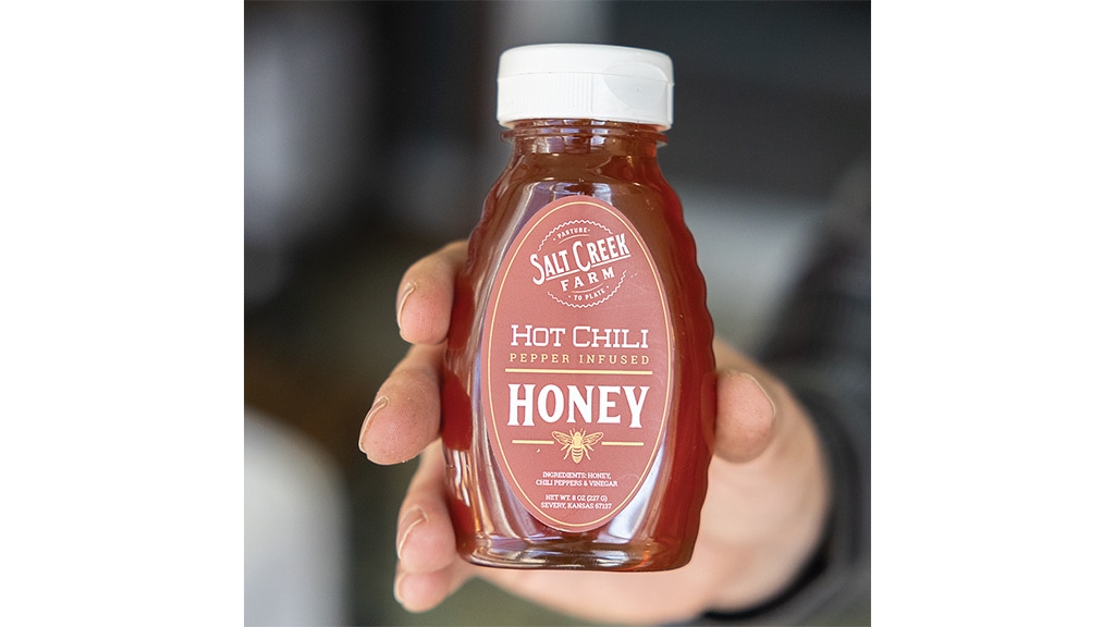 hands holding bottle of honey labelled hot chilli honey