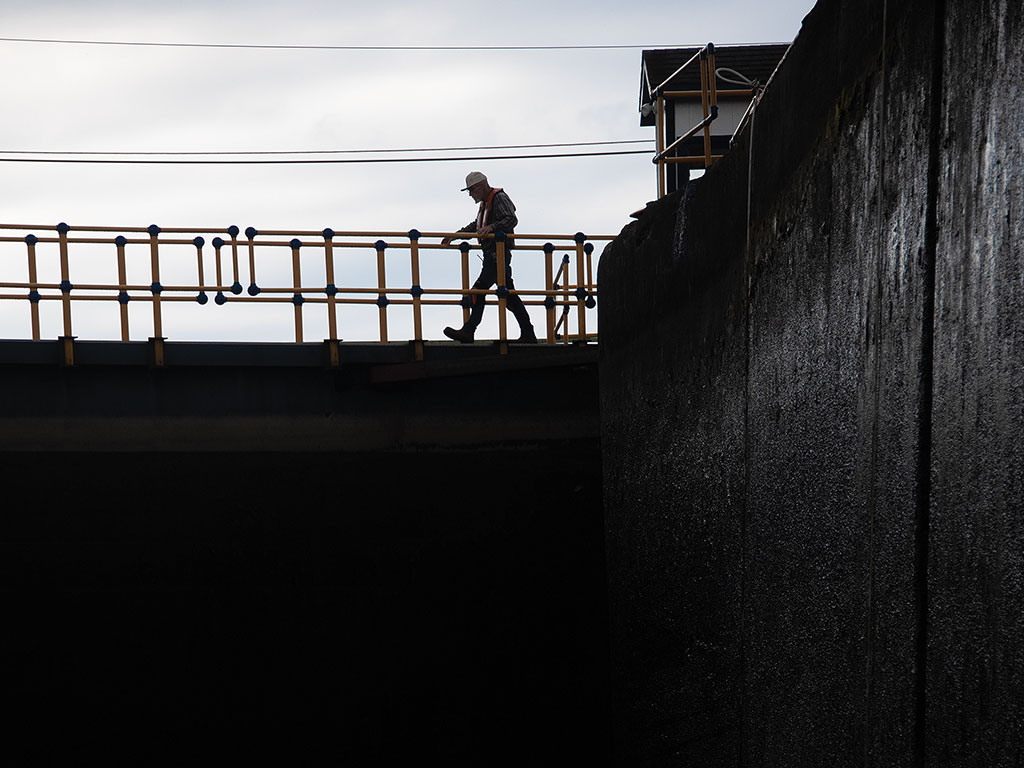 A lock keeper walks atop a gate on the Erie Canal.