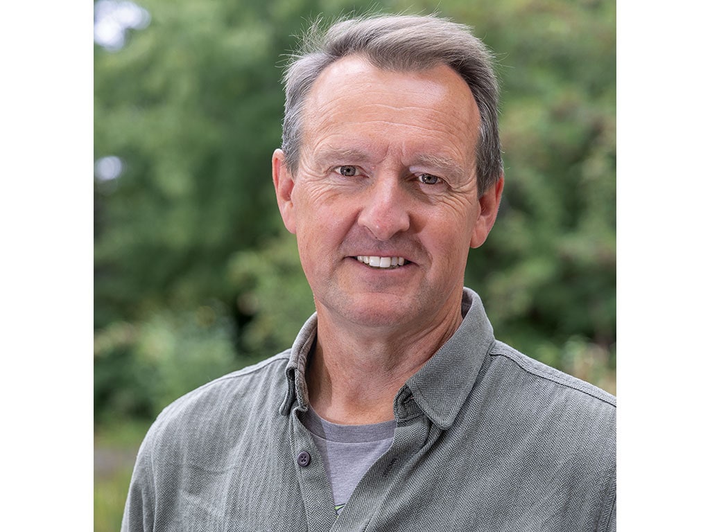 Tom Wolf wearing a grey button down shirt and smiling.