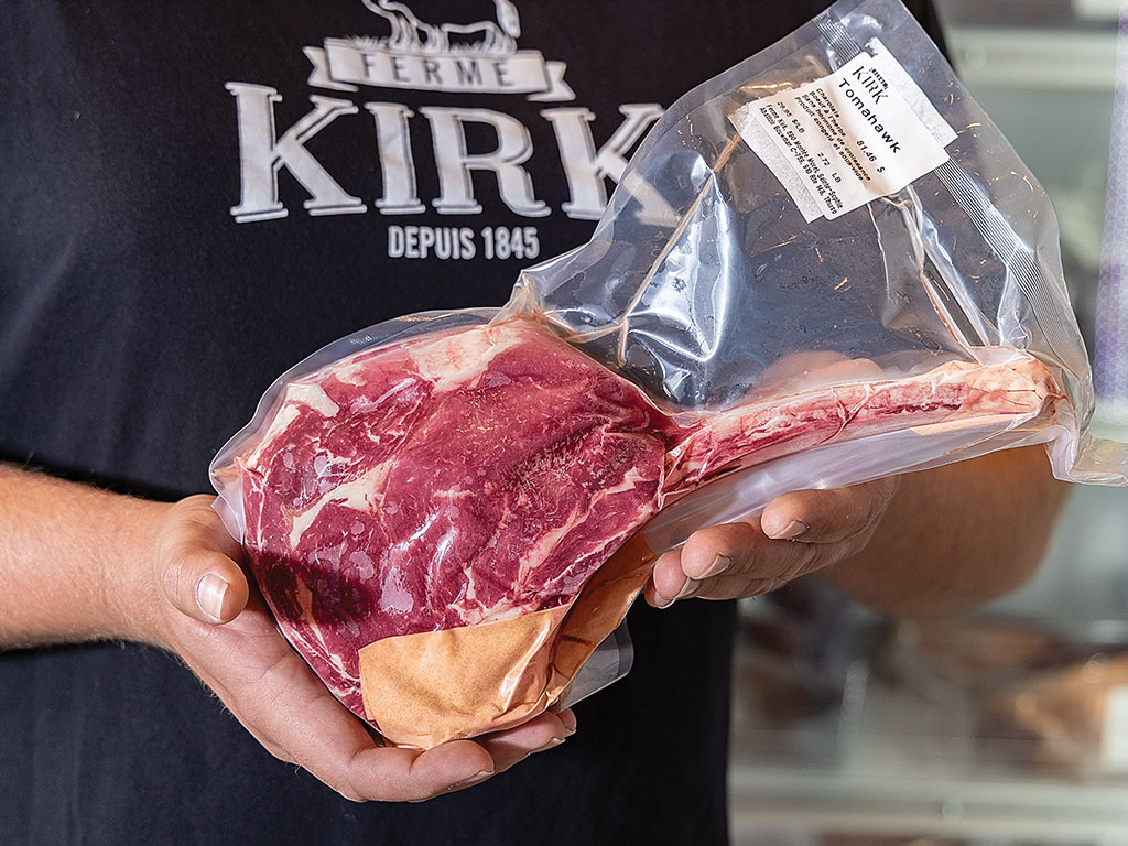 Person holding a vacuum-sealed steak with a label.