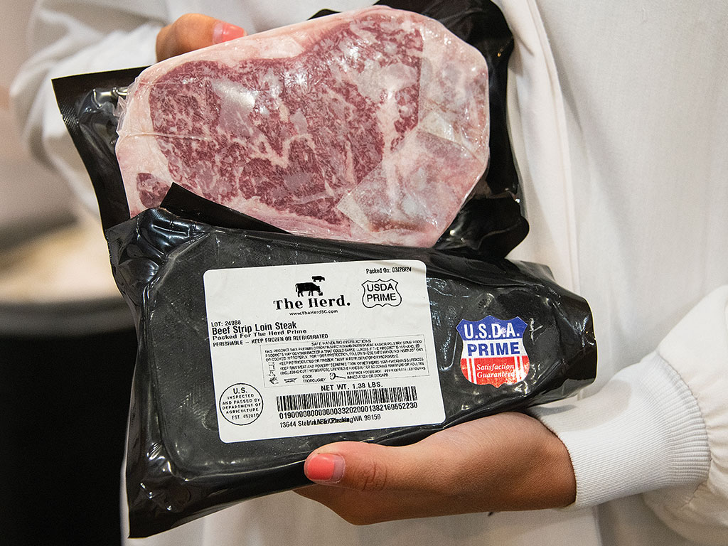 Person holding a USDA Prime Beef Sirloin Steak in vacuum packaging.