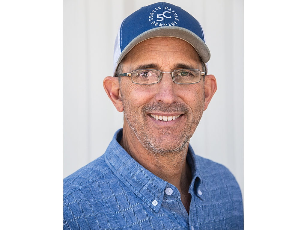 Person wearing a blue cap and textured blue shirt against a white background.